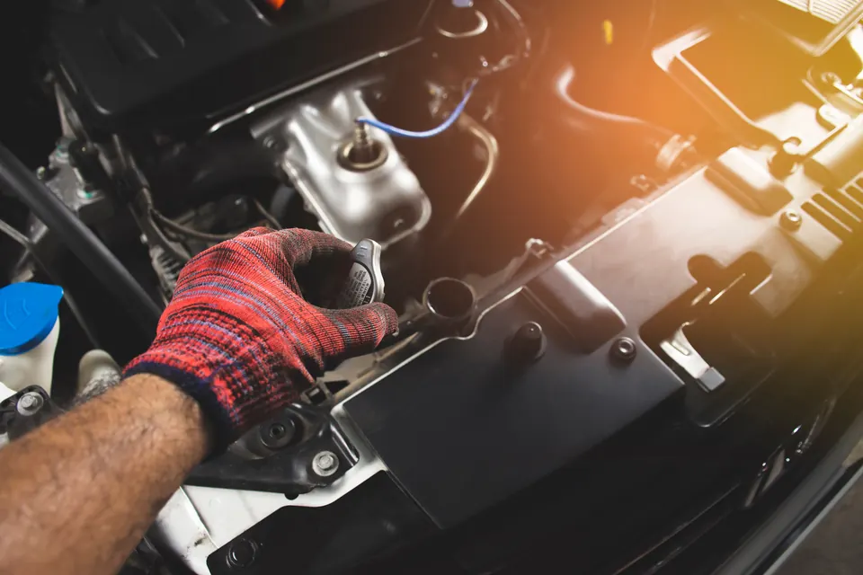 A gloved hand opening the radiator cap on an engine