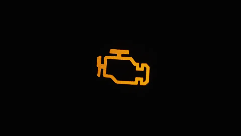 The amber check engine light lit on a dark dashboard