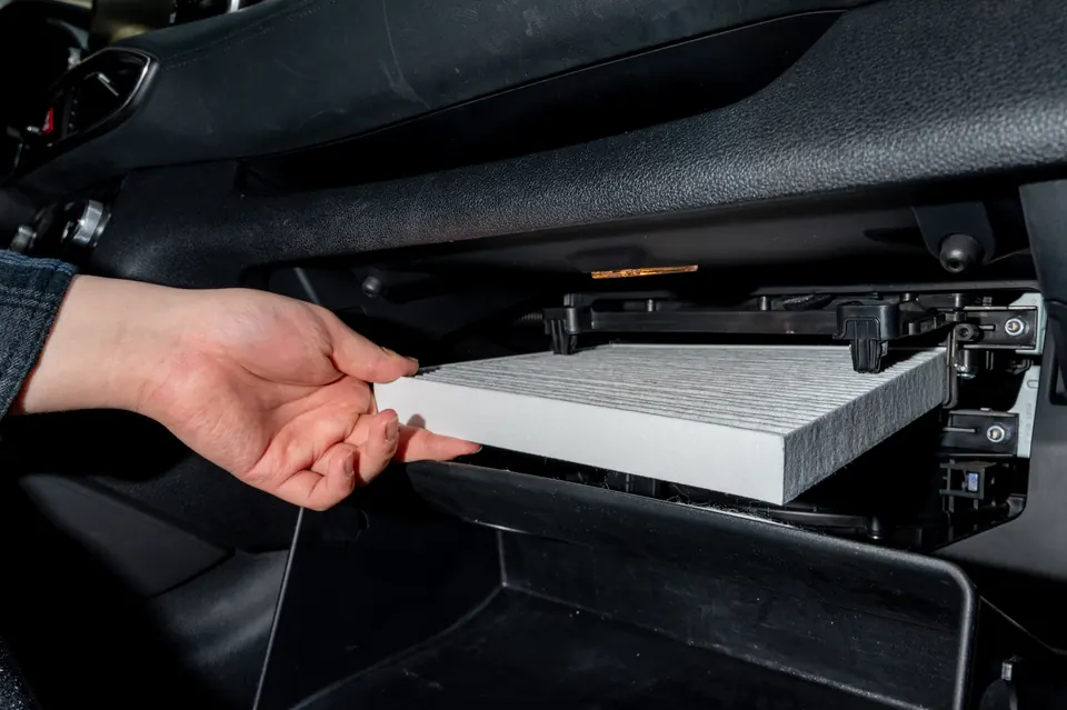 A hand sliding a new cabin air filter into its housing