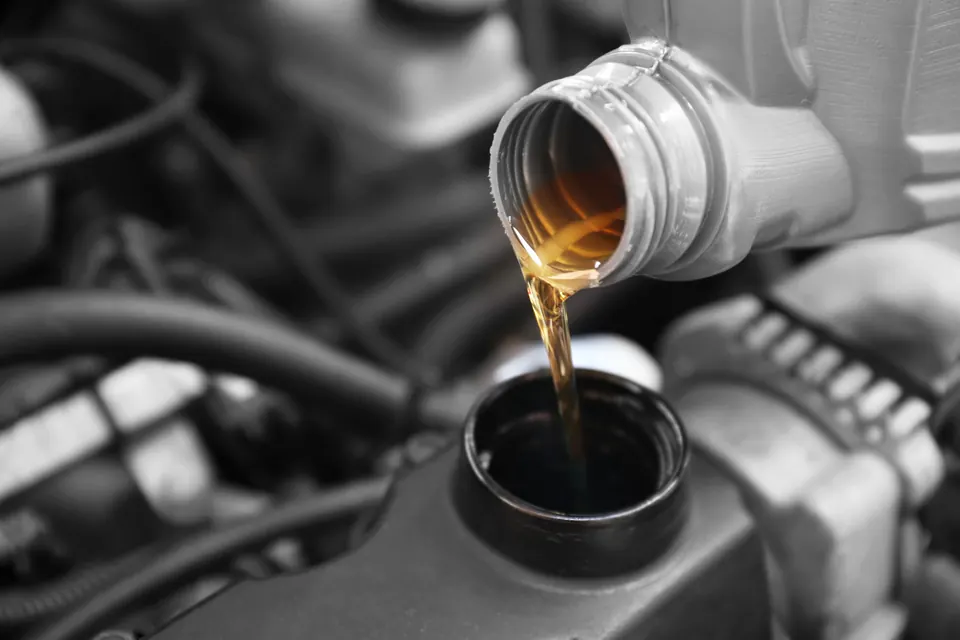 Fresh motor oil pouring into an engine's fill opening, close up
