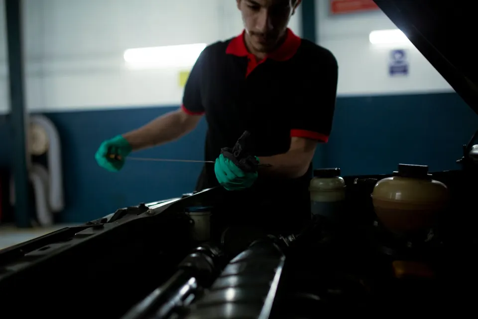 A technician wiping a dipstick to read the oil level