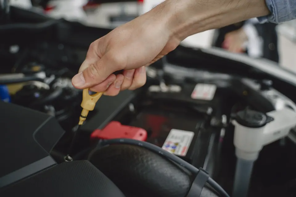 A hand pulling the oil dipstick to check the level