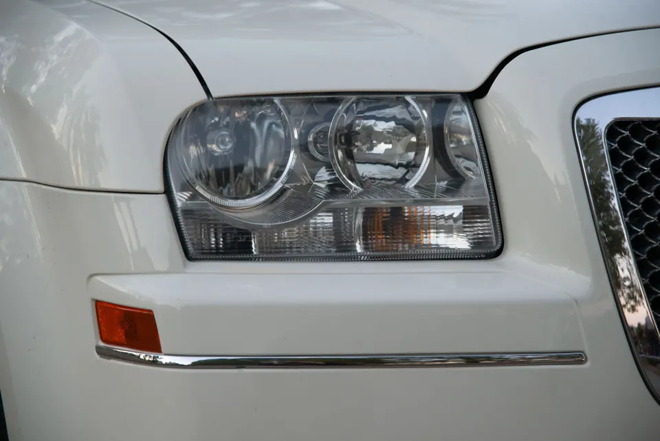The headlight of a white sedan up close