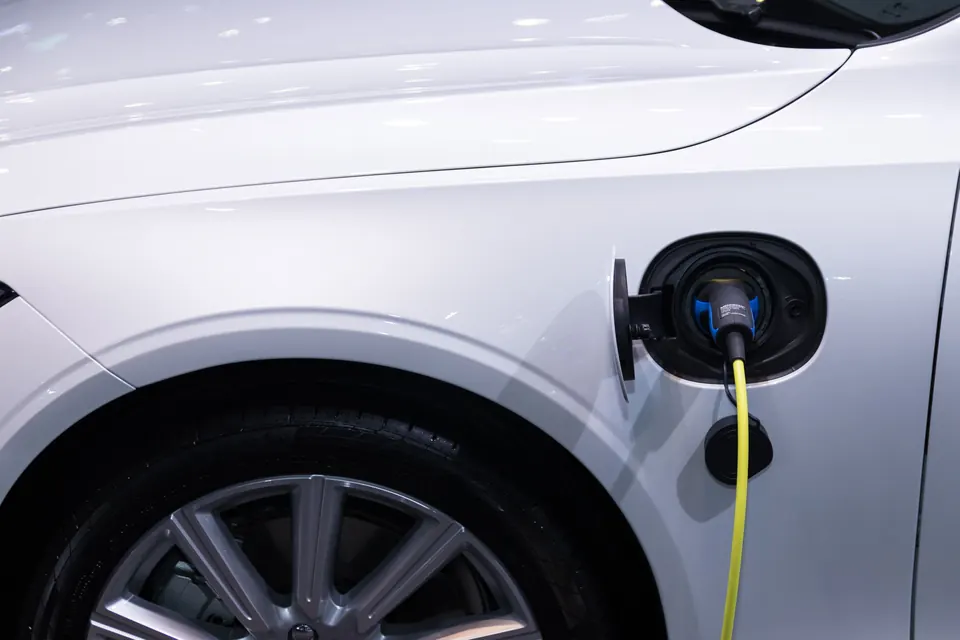 A charging cable plugged into a white car's charge port
