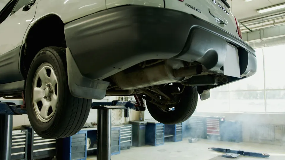 The underside of an SUV on a lift, exhaust and rear axle in view