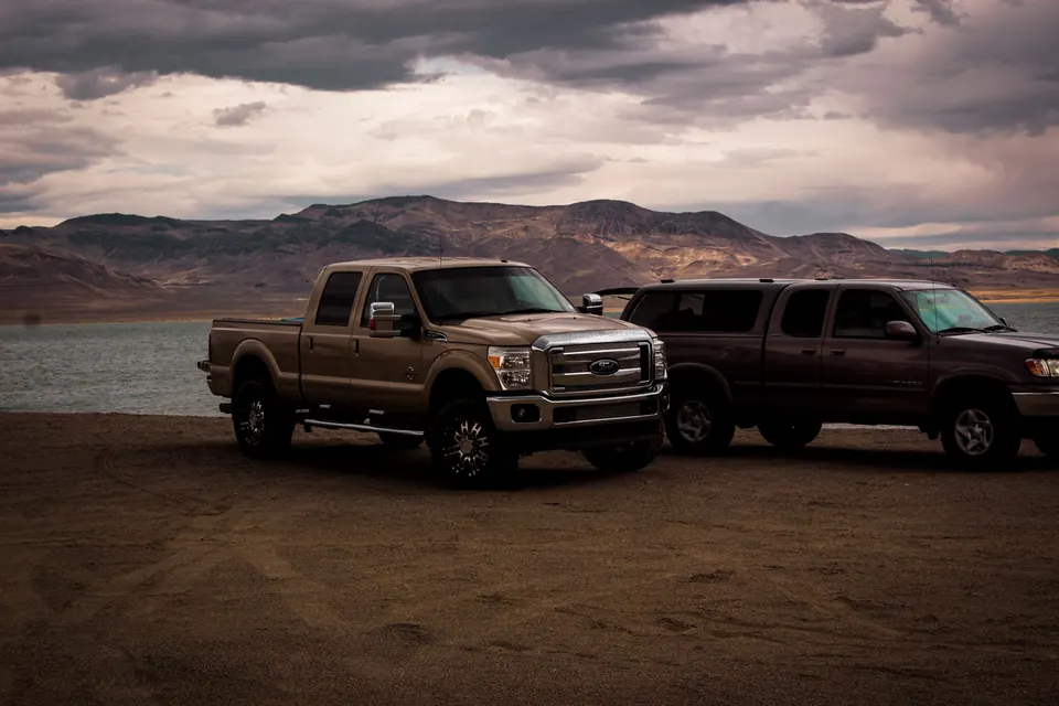 Two heavy-duty pickups parked by a high-desert lake