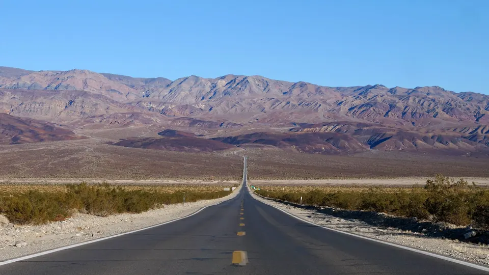 A straight desert highway running toward bare mountains