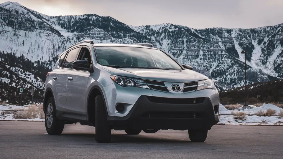 A silver compact SUV parked in front of snowy mountains