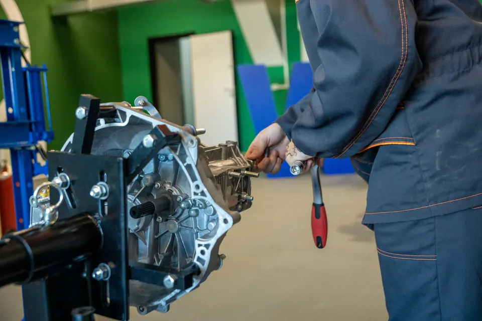 A technician working on a transmission mounted on a workstand